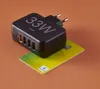 A black Hama USB charger with multiple ports sits on top of a green gift card. Anteprima dell’immagine prodotto