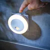 A hand is pressing a button on a plug-in LED night light with a motion sensor. Produktbild-Vorschau