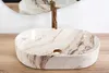 A marble-patterned vessel sink with a gold faucet is shown on a wooden countertop, with a mirror reflecting the scene. Náhľad obrázku produktu