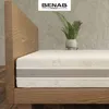 A mattress on a wooden bed frame, with a plant in a pot on a shelf in the background. Náhľad obrázku produktu