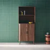 A wooden bookshelf with two doors against a green grid-patterned wall. Produktbild-Vorschau