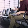 A person is sitting in an airport waiting area, charging a tablet with a power bank. Náhled obrázku produktu