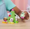 A child's hand is holding a small toy bear while other small toys are arranged around a green, pyramid-shaped structure. Produktbild-Vorschau