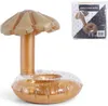 An inflatable drink holder shaped like a palm tree with a golden umbrella and base filled with gold glitter, shown on a white background. A packaged version of the product is visible in the upper right corner. Produktbild-Vorschau