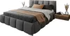 A modern upholstered bed with a headboard and a bedside table with decorative items. Produktbild-Vorschau