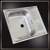 A stainless steel kitchen sink with a drainboard is shown from a slightly elevated angle against a black background with a decorative border. Náhľad obrázku produktu