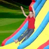 A young girl is sliding down an inflatable slide outdoors. Náhled obrázku produktu
