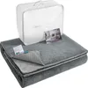 A folded gray blanket is displayed in front of a white storage bag with handles. A small marketing card is also visible. Náhled obrázku produktu