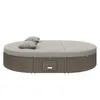 A round, rattan outdoor daybed with gray cushions and two pillows, set against a white background. Produktbild-Vorschau