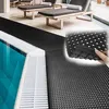 A black anti-slip mat is laid out next to a swimming pool. Podgląd zdjęcia produktu