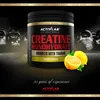 A product shot of a creatine supplement container with lemons, set against a dark, moody background with weights visible. Náhled obrázku produktu