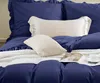 A close-up view of a neatly made bed with navy blue bedding and cream-colored pillows. Produktbild-Vorschau