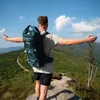 A person with a backpack on a mountain top, arms outstretched. Anteprima dell’immagine prodotto