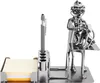 A metal desk organizer with a pen holder, sticky note holder, and a figurine of a veterinarian with a dog. Náhľad obrázku produktu