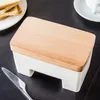 A butter dish with a wooden lid sits on a dark surface next to a knife and some toast. Podgląd zdjęcia produktu