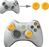 An image showing a white Xbox 360 controller with yellow thumbstick covers installed, and also showing the yellow thumbstick covers separately. Produktbild-Vorschau