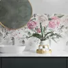 A bathroom vanity with a sink, faucet, and decorative items, featuring floral wallpaper. Náhled obrázku produktu