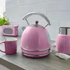 A pink retro electric kettle and mug are displayed on a kitchen counter with a pink radio in the background. Produktbild-Vorschau