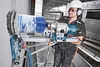 A construction worker is using a large diamond core drill to make a hole in a wall. Voir les images du produit