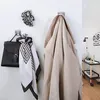 Hooks on a wall holding a coat, a bag, and scarves. Produktbild-Vorschau