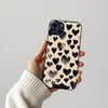 A hand holding a phone case with a heart pattern. Produktbild-Vorschau