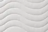 A close-up view of a white mattress with a wavy quilted pattern. Produktbild-Vorschau