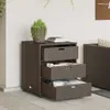 A brown poly rattan cabinet with three drawers is shown on a tiled patio next to a white wall. Náhľad obrázku produktu