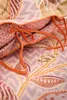 A close-up view of a bedding set with a floral pattern and orange ties. Produktbild-Vorschau