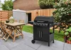 A gas grill and outdoor dining set are arranged on a patio in a backyard setting. Podgląd zdjęcia produktu