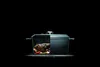 A cutaway view of a Dutch oven showing a roast and vegetables inside, with steam rising. Produktbild-Vorschau