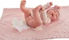 A baby doll lying on a pink blanket with a diaper. Anteprima dell’immagine prodotto
