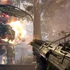 A scene from a video game showing a first-person perspective with a weapon in the foreground, an explosion and a robot in the midground, and trees and a street sign in the background. Produktbild-Vorschau