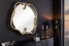 A decorative mirror with a snake sculpture frame is displayed on a dark wall above a black dresser, with candles and a lamp nearby. Produktbild-Vorschau