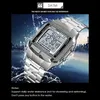 A silver digital watch with a metal band is shown against a background of splashing water and a city skyline at night. Produktbild-Vorschau