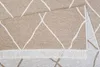 A close-up view of a beige rug with a white diamond pattern and fringe. Náhľad obrázku produktu