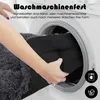 A person is placing a dark gray dog bed into a washing machine. Produktbild-Vorschau