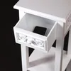 A close-up view of a white vintage-style side table with an open drawer containing a smartphone. Náhled obrázku produktu
