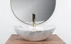A marble-effect basin with a gold faucet is shown on a wooden surface, with a round mirror in the background. Anteprima dell’immagine prodotto