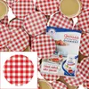 A collection of red and white checkered jar lids, with a small booklet featuring jam and strawberries. Podgląd zdjęcia produktu
