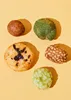 A top-down view of five different types of Japanese rice crackers arranged on a yellow background. Produktbild-Vorschau