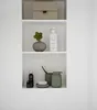 Three shelves in a white recessed wall unit, displaying various bathroom accessories and decorative items. Náhled obrázku produktu
