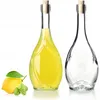 Two glass bottles, one filled with yellow liquid and the other empty, with a lemon and mint leaves in the foreground. Voir les images du produit