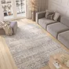 A modern living room with a gray sectional sofa, a patterned rug, an ottoman, and a coffee table. Anteprima dell’immagine prodotto
