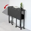A black folding table with a plant and a book on it, shown in a room with light wood flooring and white walls. Produktbild-Vorschau