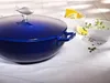 A blue cast iron pot with a fish-shaped lid handle is shown on a white tablecloth, with bowls of lemon slices and herbs in the background. Podgląd zdjęcia produktu