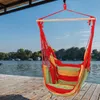 A striped hammock chair hangs over a wooden dock next to a lake. Náhled obrázku produktu