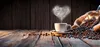 A cup of coffee with steam in the shape of a heart, next to a sack of coffee beans. Produktbild-Vorschau
