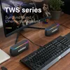Two portable speakers are placed on a wooden desk next to a computer keyboard and monitor. Produktbild-Vorschau