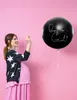 A pregnant woman is holding a large black balloon with 'Boy or Girl?' written on it. Produktbild-Vorschau