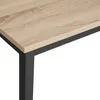 Close-up of a table with a light wood grain top and black metal legs. Náhled obrázku produktu